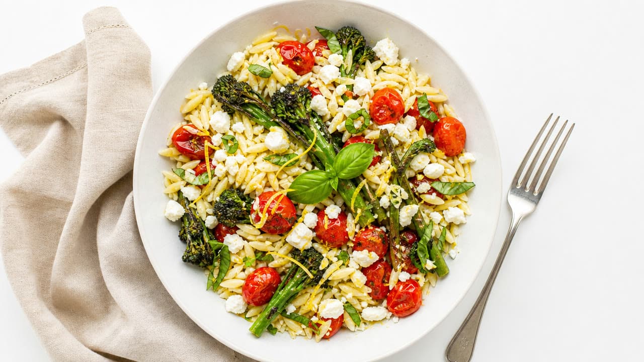 A bowl of lemony orzo with roasted tomatoes and basil